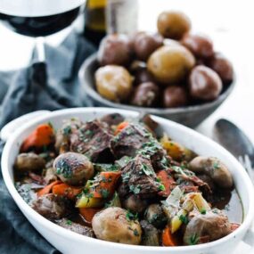 casserole dish of cooked beef with herbs, mushrooms and carrots