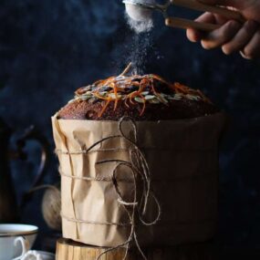 sprinkling powdered sugar onto a panettone bread cake recipe