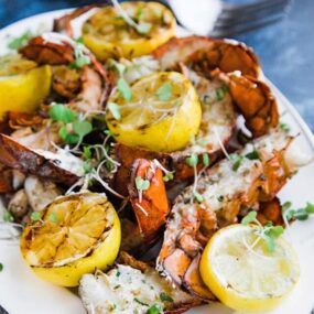 grilled lobster tails on a platter with lemons