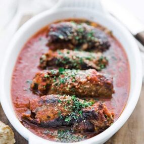 rolled seared beef in tomato sauce in a casserole dish