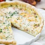 quiche lorraine recipe in a tart pan with a slice taken out