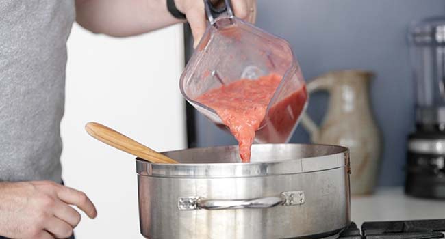 adding tomatoes to a pot