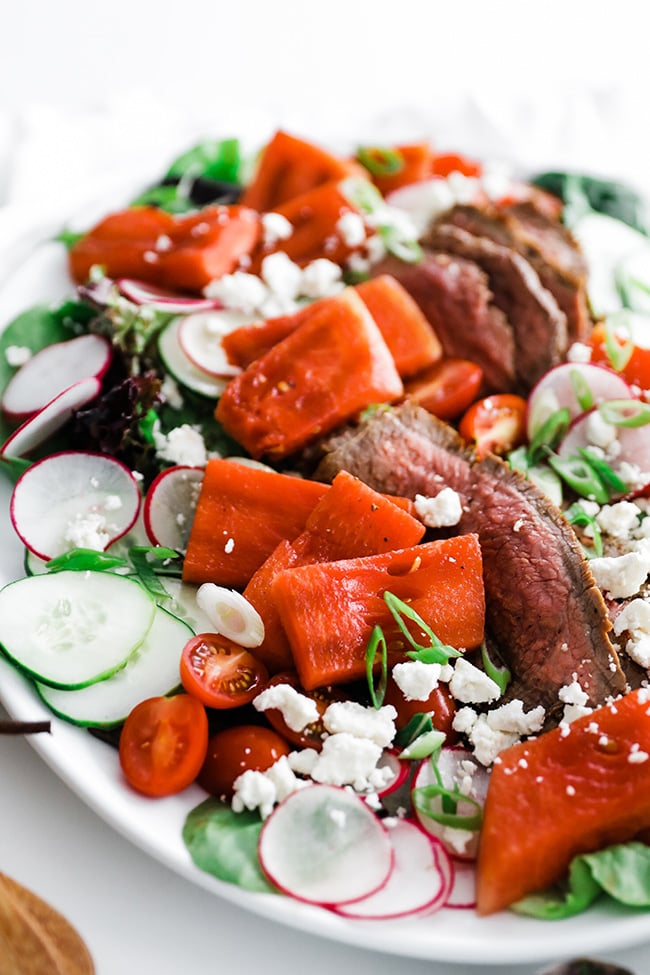 watermelon feta salad with steak on a platter