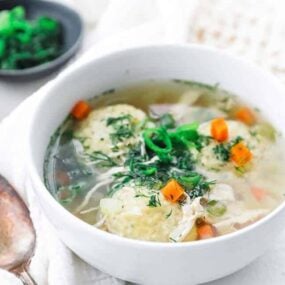 bowl of matzo ball soup with carrots and dill