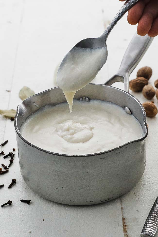 a spoon dipped in bechamel sauce