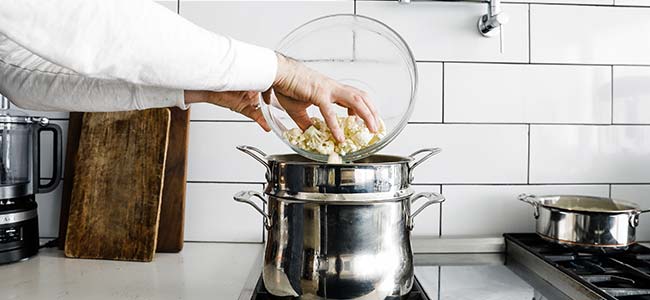 boiling a bowl of cauliflower in a pot of water