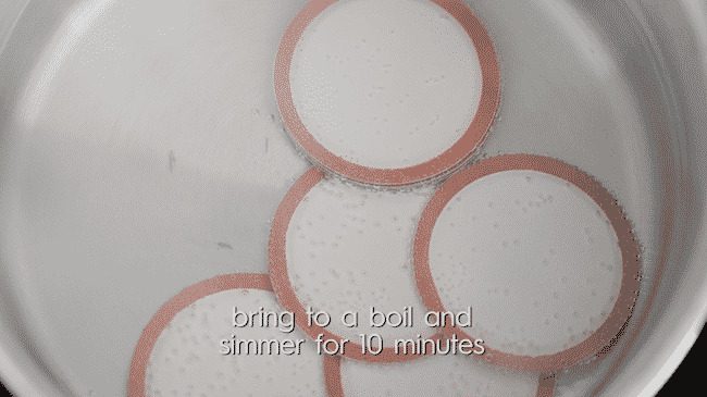 simmering mason jar lids in a medium size pot of water