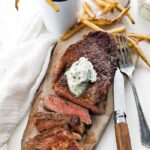 sliced steak with herb butter and fries