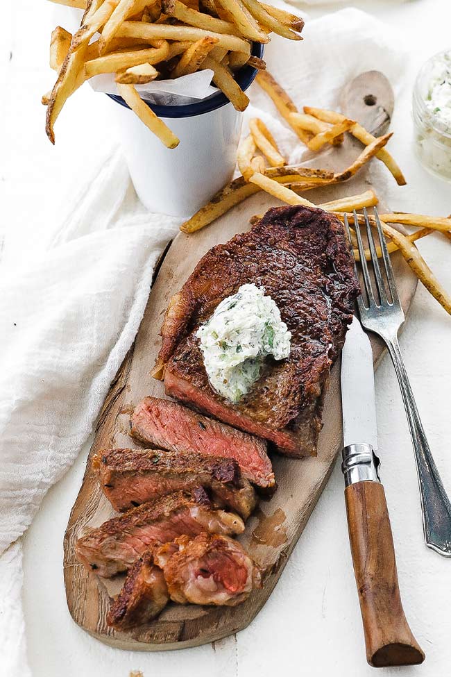 sliced steak with herb butter and fries