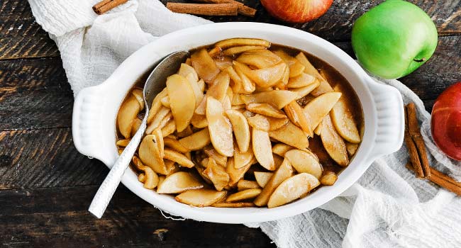 apple slices that are baked in a dish with brown sugar and butter