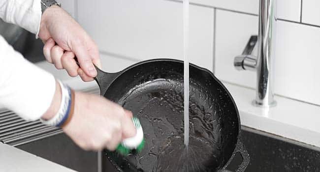 scrubbing a pan under water