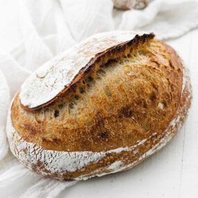 Whole loaf of sourdough bread with a bread towel