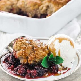 blackberry cobbler on a plate with caramel, ice cream and mint