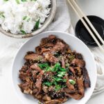 beef bulgogi in a bowl next to rice and veggies