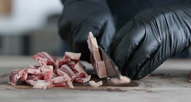 thinly slicing ribeye steak on a cutting board