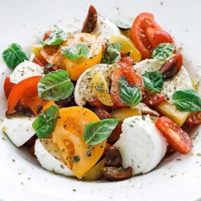 bowl of sliced tomatoes, cheese and herbs