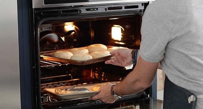 adding bagels on a sheet tray to the oven