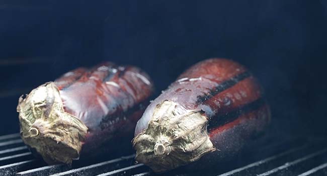 whole eggplant cooking on a grill