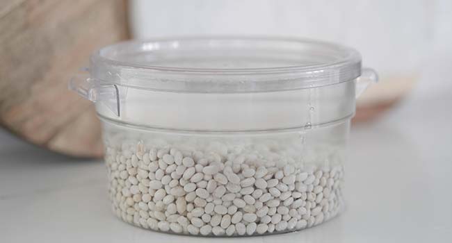 navy beans soaking in water in a container