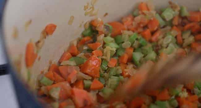 mixing onions, celery, and carrots with flour to make a roux