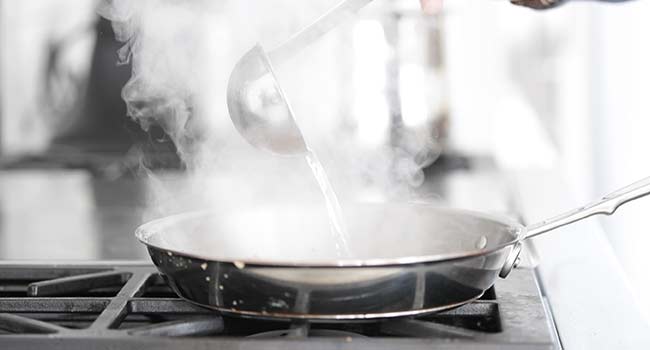 adding hot pasta water to a pan