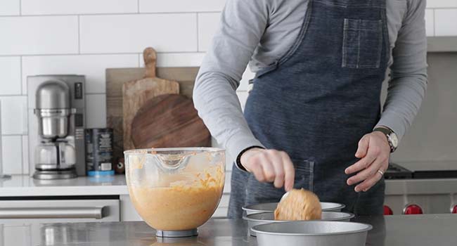 transferring carrot cake batter to cake pans