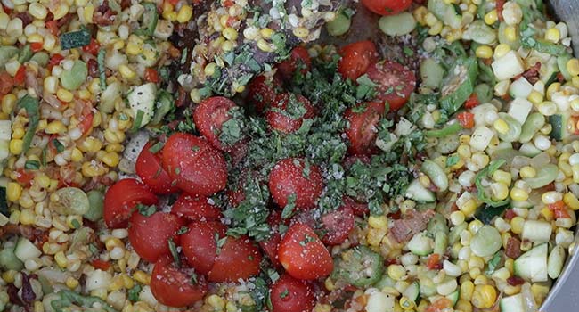 adding tomatoes to a succotash