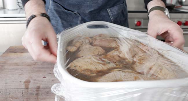 coating marinated chicken in plastic wrap