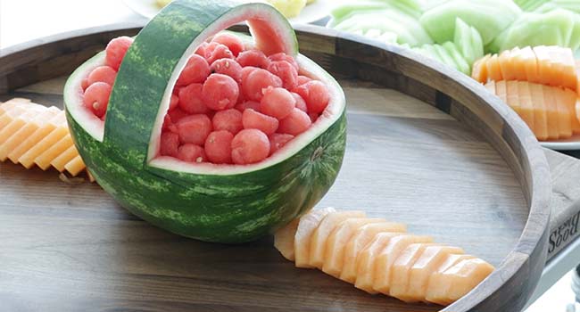 adding sliced cantaloupe to a tray