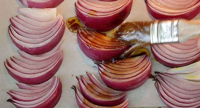 brushing sliced onions with balsamic