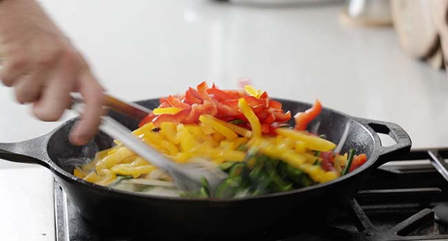 adding peppers and onions to a skillet