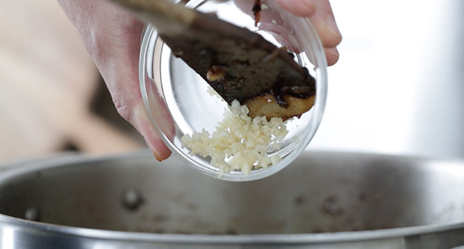 adding garlic to a pan