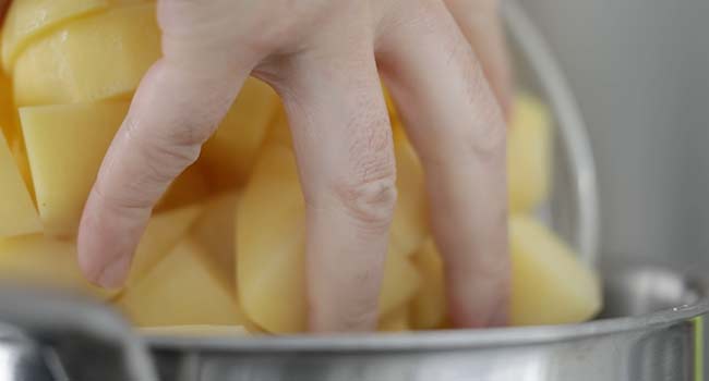 adding potatoes to a pot of water