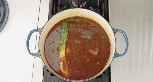 beef stock in a pot with herbs