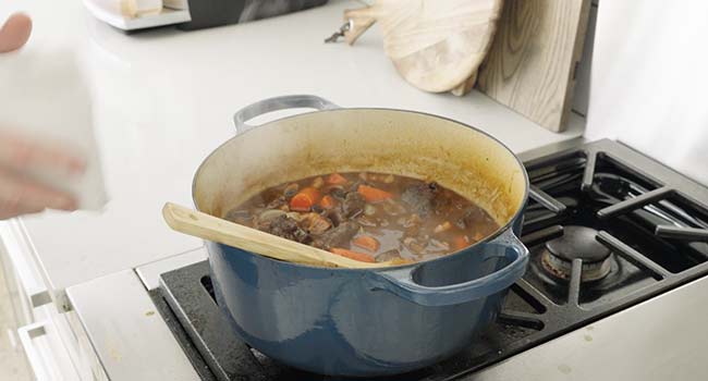 adding beef into a pot of stock and veggies