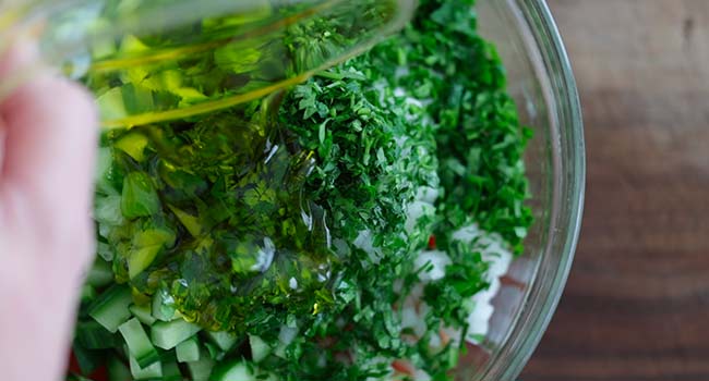 adding olive oil to an Israeli salad