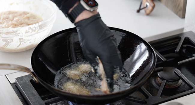 adding chicken to a wok