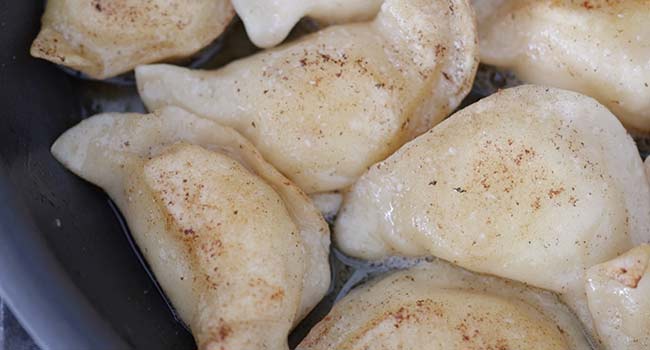 searing pierogi in a pan of butter