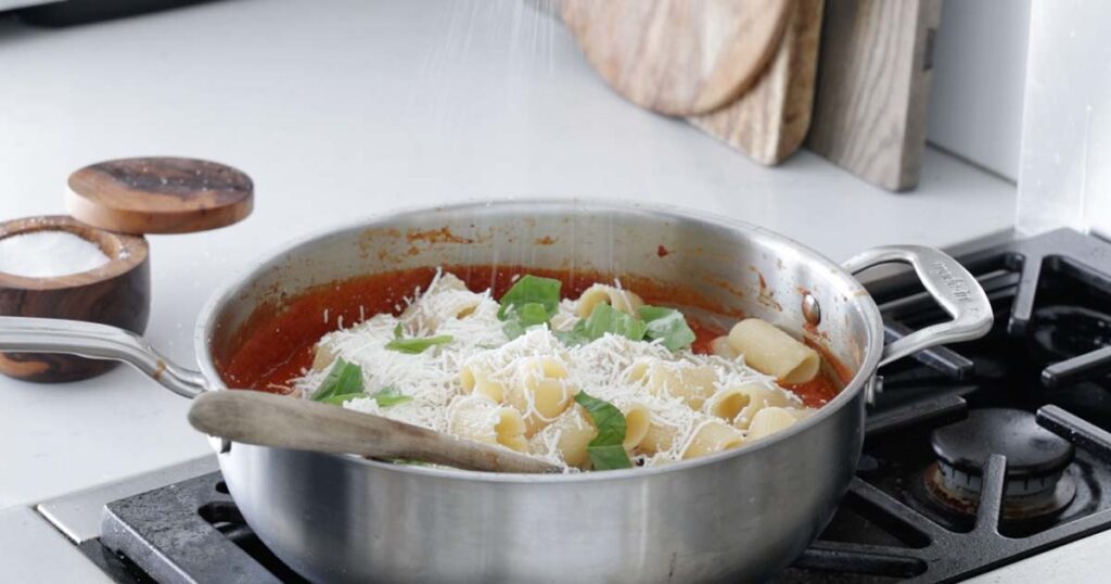 adding cheese and pasta to tomato sauce