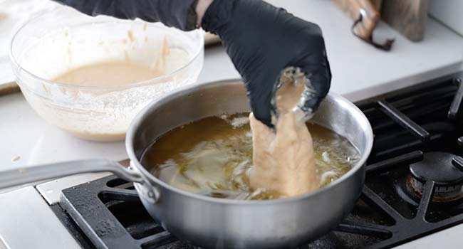 adding battered fish to hot oil