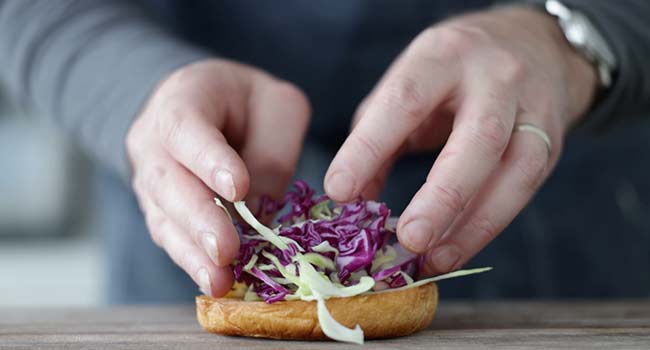 adding cabbage to a bun