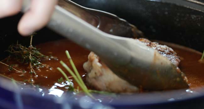 adding veal shanks to a pot of broth