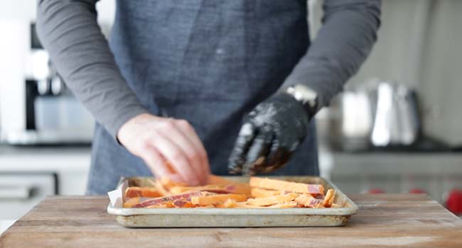 spreading sweet potato fries out on a sheet tray