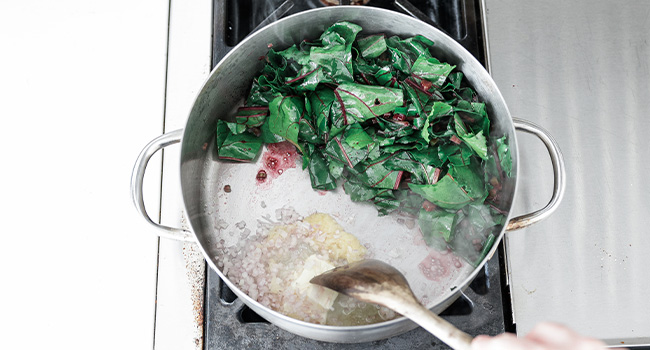 cooking garlic and shallots with beet greens