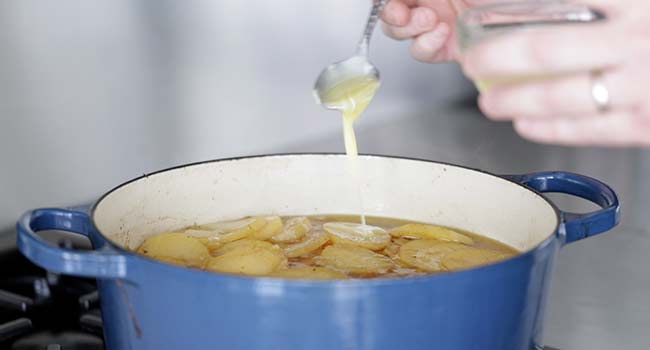 drizzling butter onto potatoes in a pot