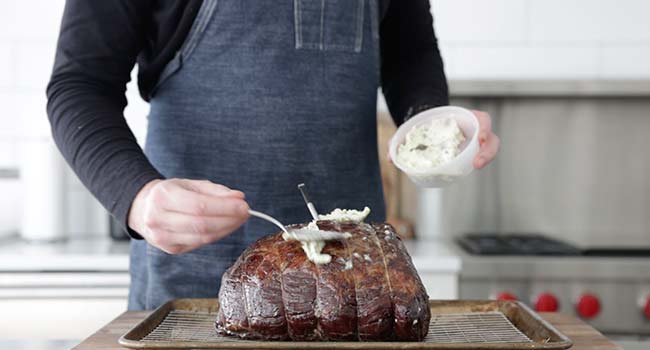 adding butter to a roast beef