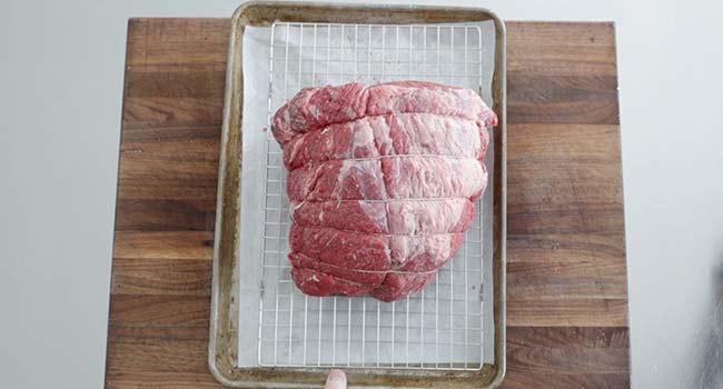 adding a trussed cut of beef to a rack