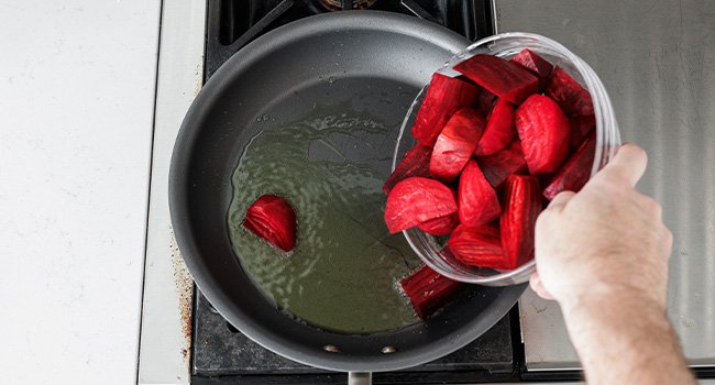 adding beets to a hot pan with oil