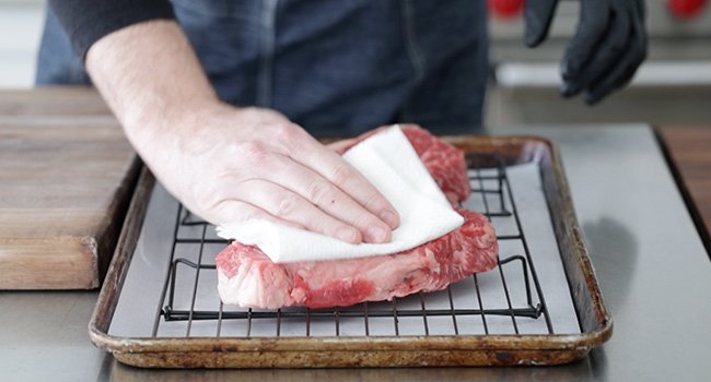 patting dry steaks with paper towels