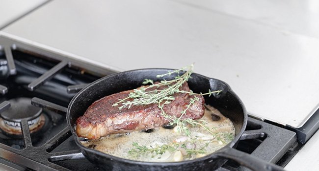 adding herbs and butter to a pan